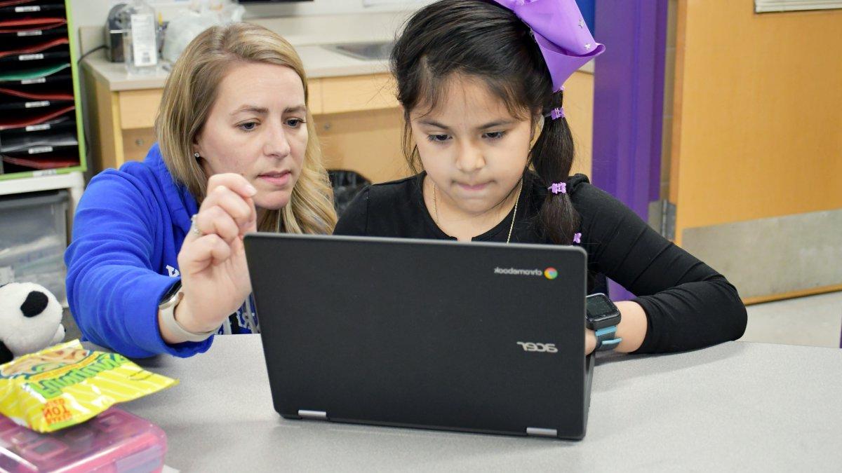 teacher helping a student on computer